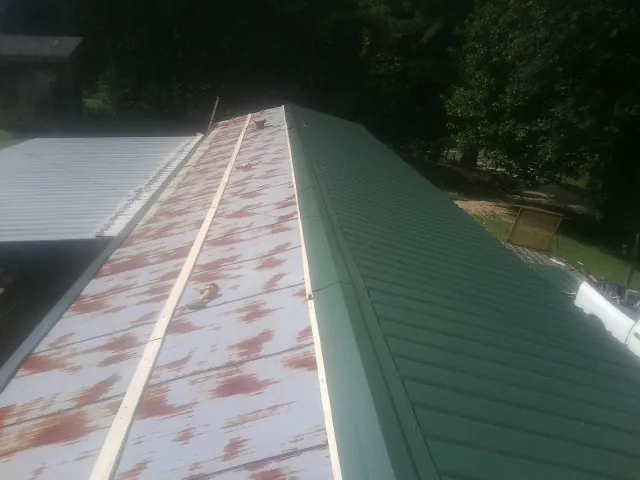 Old rusted panels beside newly installed green metal roofing — Wind Damage Roof Repair by Roofing Brothers in Garden City